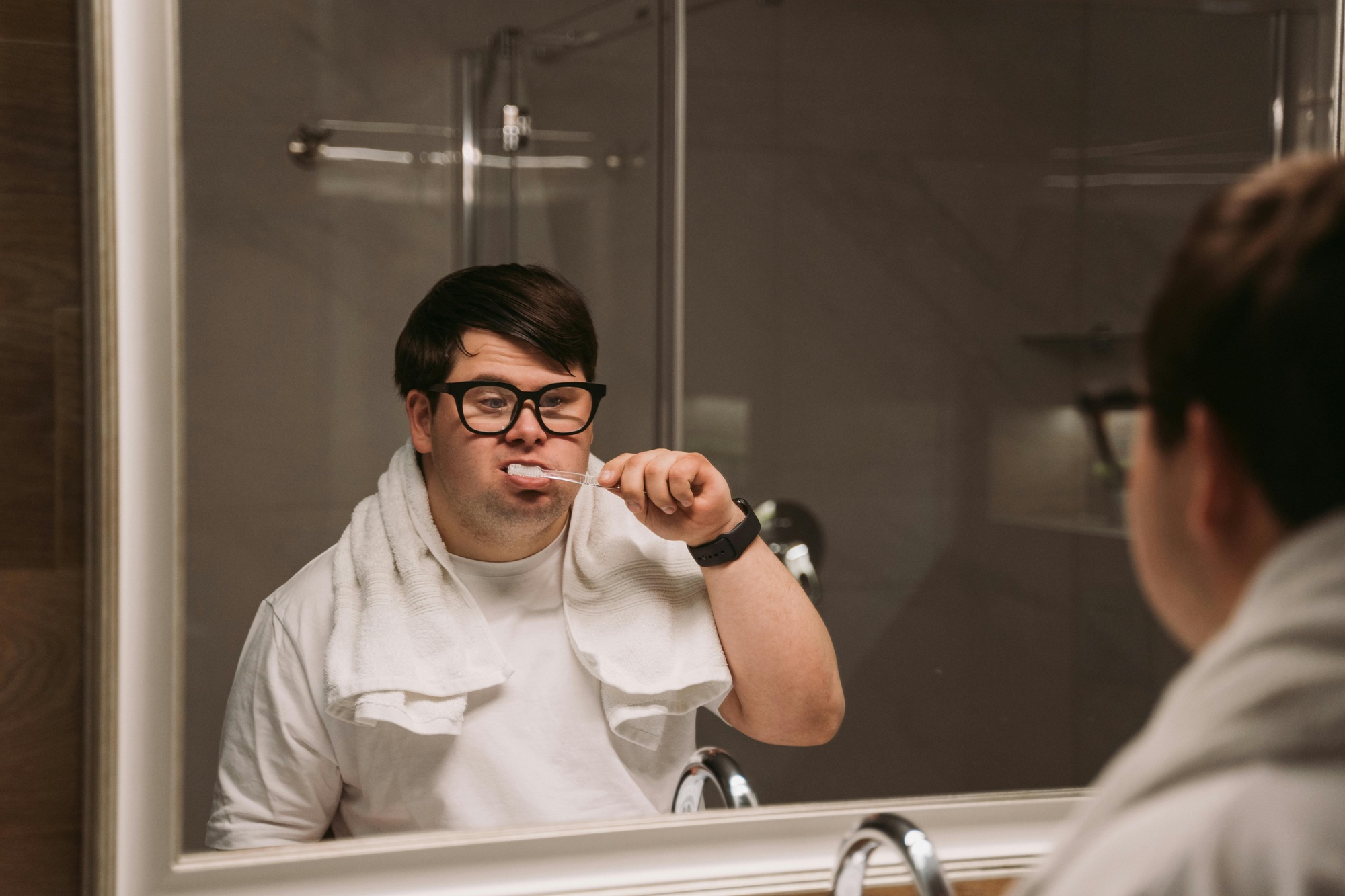 Man with special needs looking in the mirror brushing teeth